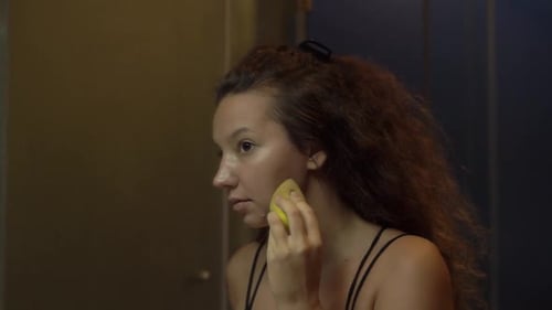 Woman Applying Makeup with Sponge in Bathroom