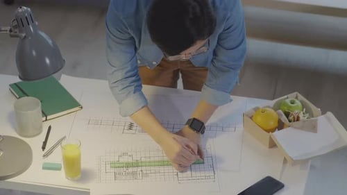 Man Drawing Architectural Plan at Office Desk