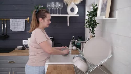 Woman Washing Dishes in Bright Kitchen