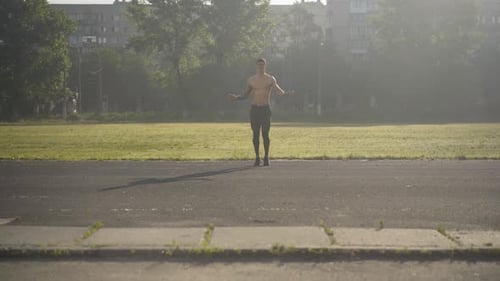 Muscular Man Jumping Rope Outdoors in Urban Park