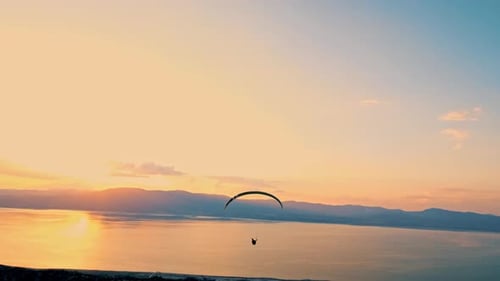 Silhouette de parapente volant dans les airs contre le coucher du soleil