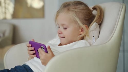 Girl Using Mobile Phone in Chair at Home