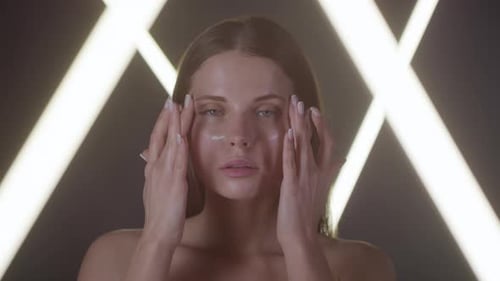 Glamorous Woman Applying Cream in Studio Setting