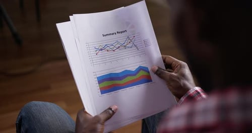 Man Analyzing Summary Report with Charts and Graphs