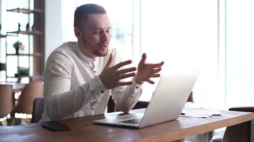 Handsome Young Business Man Is Making Video Call Conferencing on Laptop at Desk