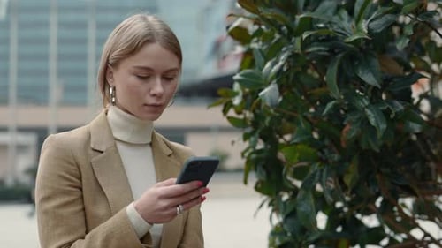Pleasant Woman in Business Suit Using Smartphone on Street