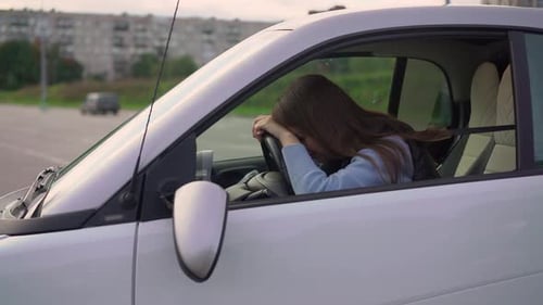 Woman Sits in Car in Urban Location