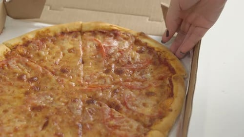 Hand Reaching for Pizza Slice in Pizza Box