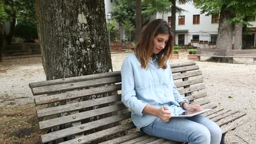 Young Woman Using Tablet on Park Bench