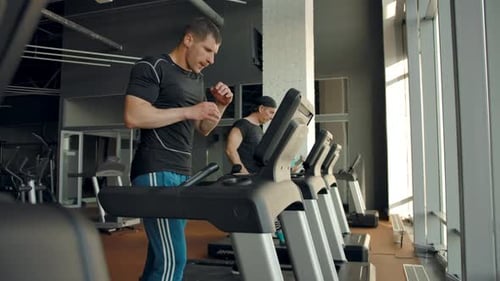 Man Runs on Treadmill at Gym in Daytime