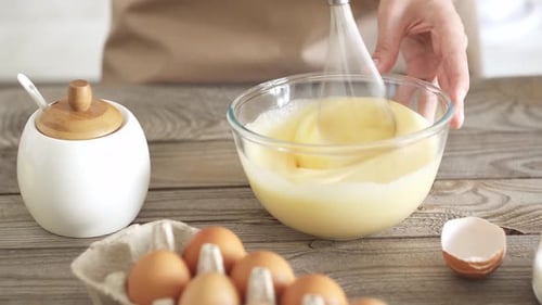 Girl Chef bate los ingredientes de la masa en un tazón de vidrio para batir con un batidor. Receta de masa casera