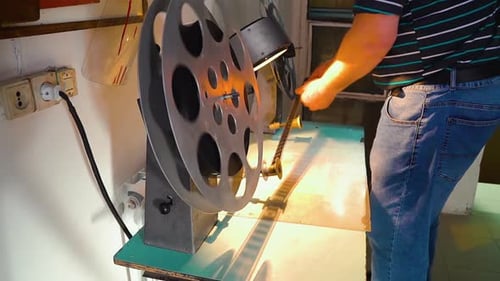 Man Loads Film onto Vintage Editing Machine