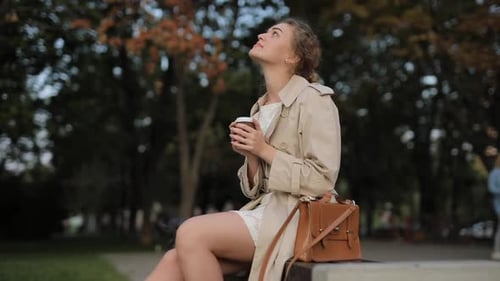 Woman Drinks Coffee on Park Bench