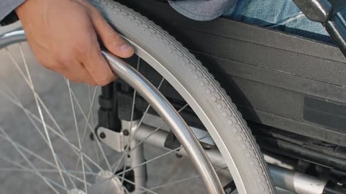 Hand on Wheel of Wheelchair During Walk in Park