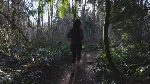 Caucasian Woman Trail Running in the Green Forest