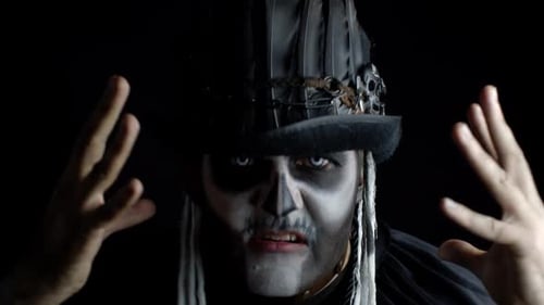 Sinister Man with Horrible Halloween Skeleton Makeup Appearing From Darkness When Light Falls on Him