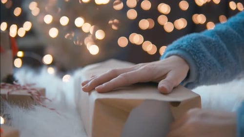 Hands Wrapping a Christmas Gift at Night