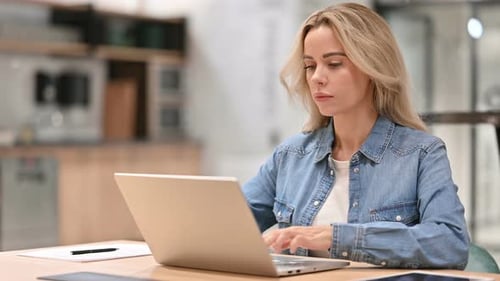 Woman Working on Laptop at Table Indoors