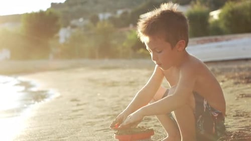 The Boy Plays in the Sand on the Beach