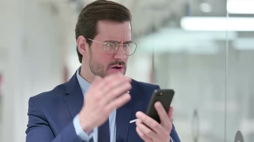 Man in Suit Disapprovingly Uses Smartphone