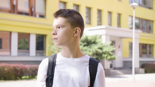 A Caucasian Teenage Boy Looks Around a School in the Background
