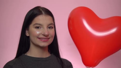 Smiling Woman Holding Red Heart Balloon