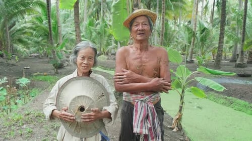 Portrait of Asian senior elder older couple farmer working in the coconut farm and look at camera.