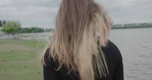Happy Girl Corrects Her Blowing Hair Turns to Camera and Smiling During Walk