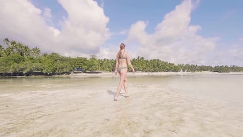 Young Woman in Bikini Walking on Sea Water at Sandy Beach on Paradise Resort. Low Angle View