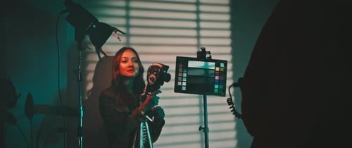 Woman Holds Camera in Studio with Lighting