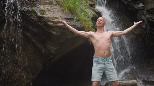 Man Enjoys Vibrations of Wild Nature Power Near Waterfall