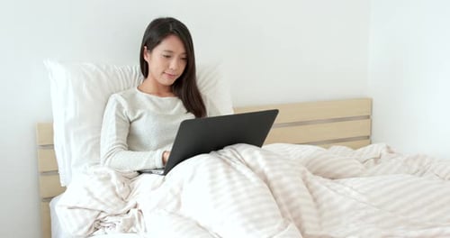 Woman Using Laptop in Bed in Bright Room