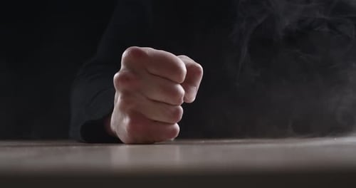 Close Up Evil Man Beats His Fist on the Table Showing Aggression on Dark Background