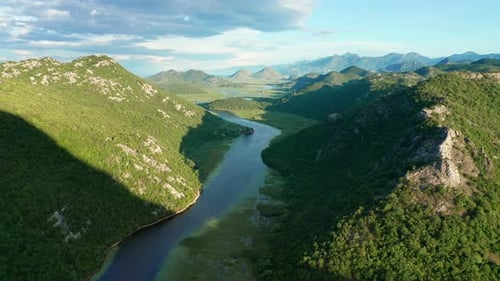 Bends and curves of blue river flowing through green valley toward distant mountains.
