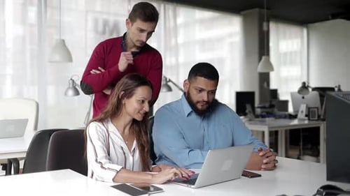Team Collaborating on a Laptop in Modern Office