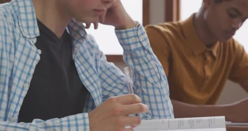 Caucasian boy writing in high school class