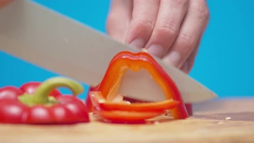 Knife Slicing Red Bell Pepper on Cutting Board