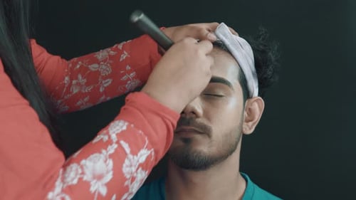 Close up of man's face and make up artist putting on his face a face powder with make up brush