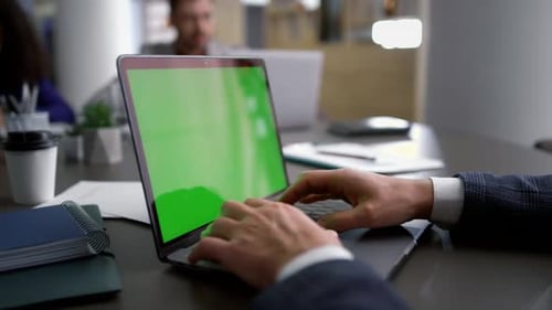 Man Typing on Laptop with Green Screen in Office