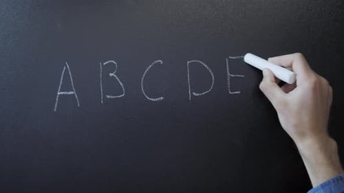 Hand Writing Alphabet With Chalk on Blackboard