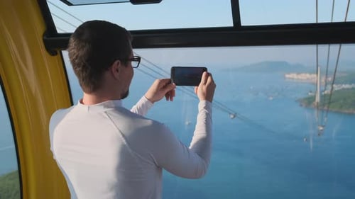 Man inside Cable Car Taking Pictures of Ocean