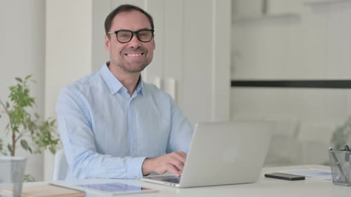 Man Smiles While Typing on Laptop Computer