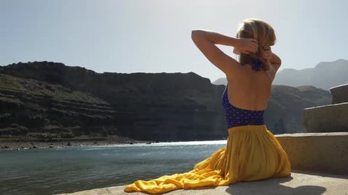 Woman Puts Up Hair by the Coast
