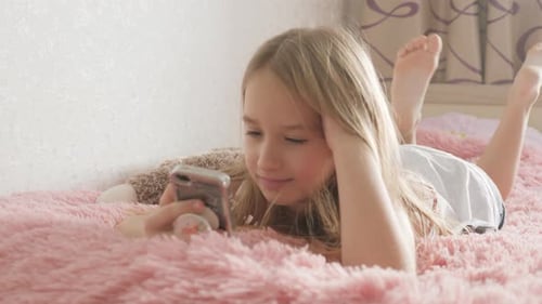 Girl Lies on Bed Using Smartphone