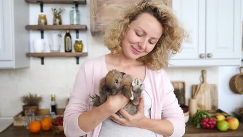 Woman Cuddles Cute Bunny Rabbit in Kitchen