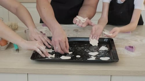 Familie legt rohe Kekse auf ein Backblech