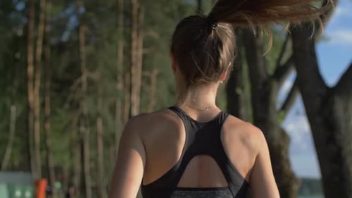 Jovem mulher com uma figura esbelta em roupas de ginástica correndo no parque