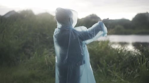 Individual in Poncho Standing in Grassy Field