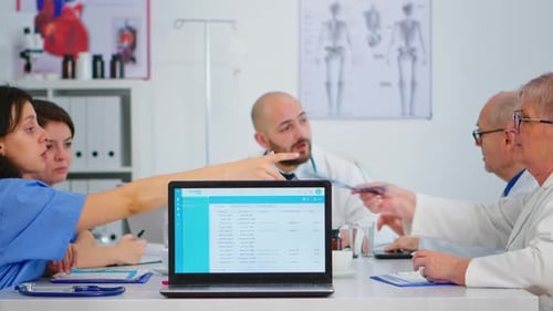 Group of Doctors Brainstorming Sitting on Desk in Hospital Meeting Office