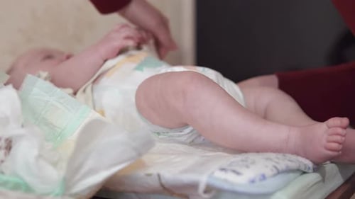Infant Lying on Back While Adult Changes Diaper